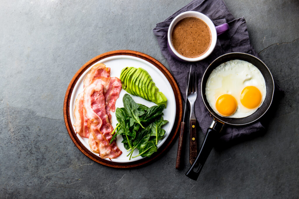 Ketogenic diet breakfast. fried egg, bacon and avocado, spinach and bulletproof coffee. Low carb high fat breakfast.